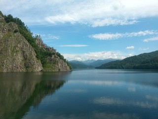 Fototapeta na wymiar lake mirroring rocky mountains with forest fir trees on summer season