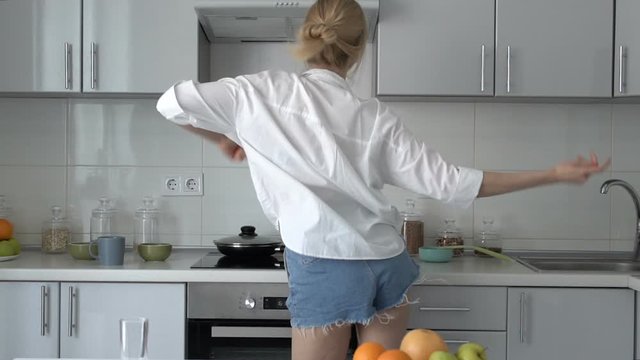 Seductive woman shaking body on kitchen, cooking breakfast, slow-mo, back-view