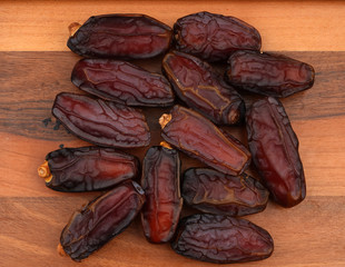 Heap of organic pitted dates isolated on wooden, top view
