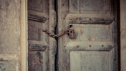Green door with rusted padlock on the surface