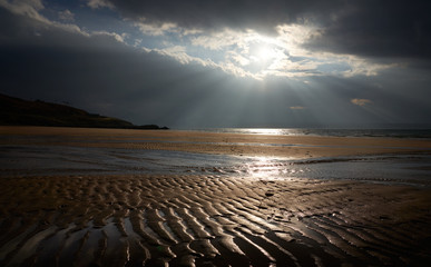 Obraz premium Rays of autumn sunlight breaking through the cloud over the rippled sands of Big Sand beach near Gairloch in the Scottish Highlands, Scotland, UK.
