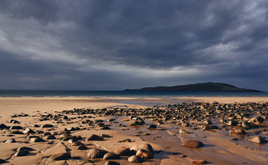 Warm sun breaking through the cloud over Big Sand beach with Longa Island in the distance near Gairloch in the Scottish Highlands, UK.
