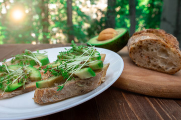 sandwiches with avocado and cressalate microgreens on a white plate on a window background. healthy diet. feed option. vegetarianism.
