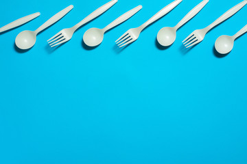 eco-friendly disposable tableware on a blue background. isolate. corn starch spoons and forks. biodegradable dishes. natural materials for replacing plastic. place for text