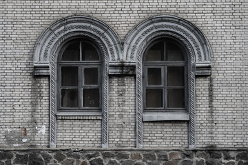 Two old ached windows on the brick wall of an abandoned old building in the style of the Stalinist...