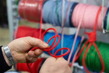 Man's hands showing how to make yacht knot with red rope