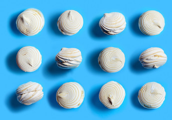 Twelve vanilla marshmallows on a blue background flat lay