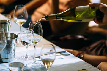 Waiter hand pouring wine in a glass served table
