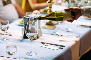 Waiter hand pouring wine in a glass served table