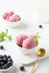 Blueberry ice cream in bowls on white background. Close up. Vertical.