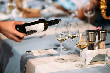 Waiter hand pouring wine in a glass served table