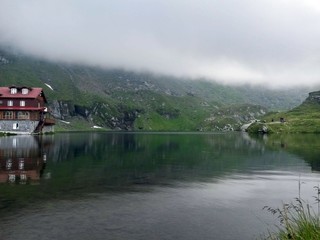 Fototapeta na wymiar chalet reflecting in glacier lake on cloudy day