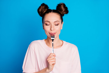 Photo of attractive satisfied lady two funny buns metal fork inside mouth eyes closed try tasty...
