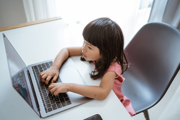 little asian female kid using laptop at home