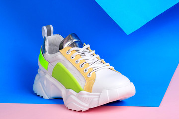 White sneakers on blue and pink background. Creative sport footwear design concept. Women or teenager shoes.