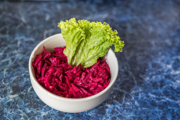 
Beetroot salad with lettuce in a white plate on a blue vintage background for a balanced diet.