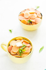 Mini pancake cereal in light green mug, white concrete background ready to serve on breakfast. New food trend during covid-19. Copy space for text. Butter and mint leaves, milk, checkered aqua cloth