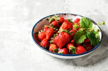 Fresh strawberries in a bowl on a gray background, still life