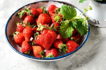 Fresh strawberries in a bowl on a gray background, still life