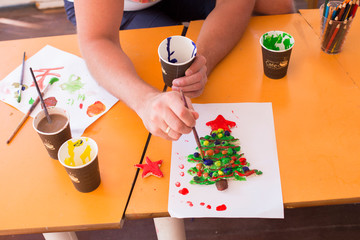 
A woman paints on a craft made of dough in the form of a Christmas tree.