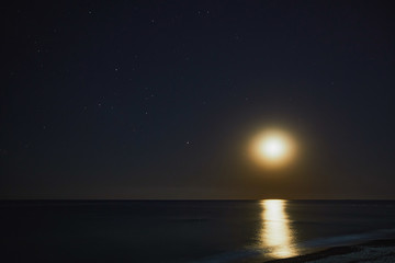 Sea shore. The moon shines and the stars are visible. You can also see the shoreline.