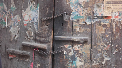 Wooden door with torn signs on surface