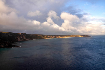 Clouds over the rocky shore, partly illuminated by the sun. Australia