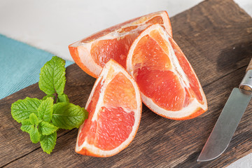 Closeup of fresh juice grapefruit with green sappy leaves of mint, refreshing fruits and herbs on wooden board