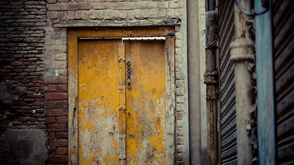 Yellow wooden door with a chain lock with brick wall