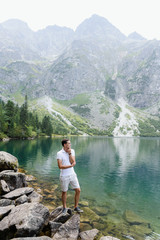 Fototapeta na wymiar The man in white clothes stands on the wonderful lake and mountains background