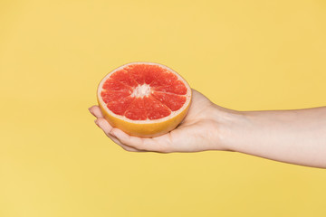 Woman holding grapefruit against a yellow background