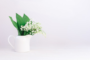 Romantic bouquet of the lilies of the valley in a jar on a white background.