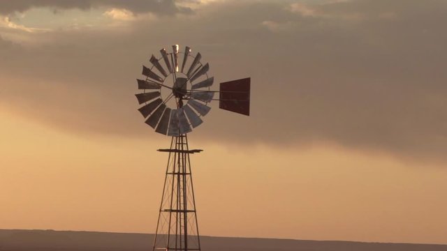 Panning shot of traditional old-fashioned windmill against sky, metallic structure during sunset - Swakopmund, Namibia