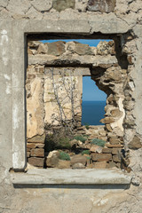 View through old abandoned dilapidated building with plants inside on the seashore
