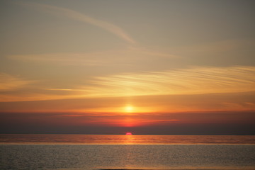 Dramatic sunset at sea. The sun set halfway over the horizon