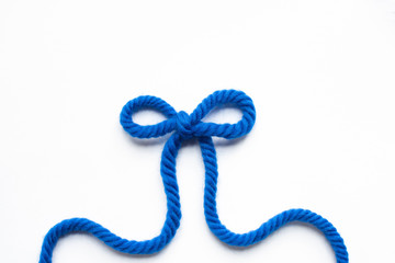 top view of bow made of blue wool yarn on white background