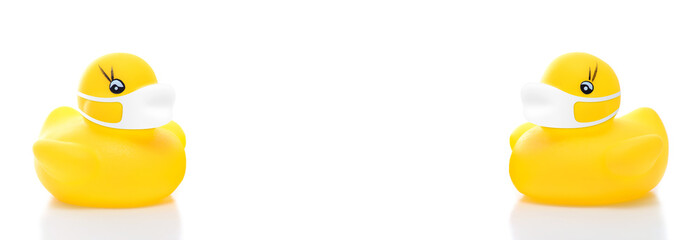 yellow rubber duck bath toy set wearing face masks on white background, concept of social distancing flu prevention