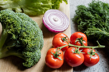 fresh ripe vegetables on cutting board on grey concrete surface