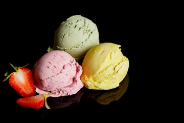 delicious lemon, strawberry and mint ice cream balls isolated on black