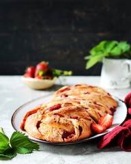 Yeast babka with strawberries and sugar in a dish on a gray background