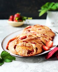 Yeast babka with strawberries and sugar in a dish on a gray background
