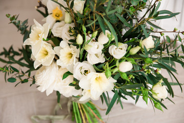 Modern large spring wedding bouquet with daffodils, ranunculus and various greens, close up