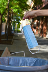 Woman throwing a face mask in the trash as a symbol of leaving the coronavirus behind