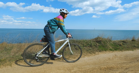 Naklejka premium Young woman bicycle rider in helmet in sunny summer day 