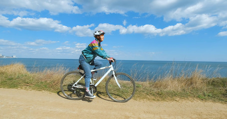 Obraz premium Young woman bicycle rider in helmet in sunny summer day 