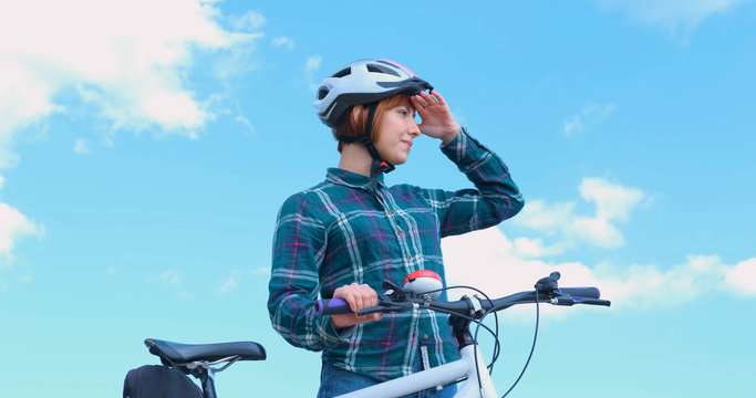 Young woman bicycle rider in helmet in sunny summer day	