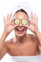 Lovely brunette using cucumber as a natural skin remedy