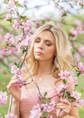 Fototapeta premium portrait of a blonde woman in pink flowers. Spring garden