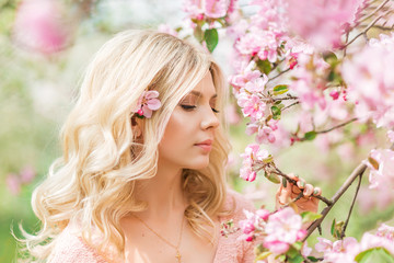 portrait of a beautiful blonde girl in a spring garden. Pink Apple blossoms