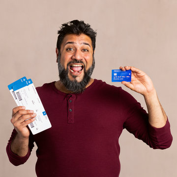 Excited Indian man holding a credit card and fligh tickets mockup